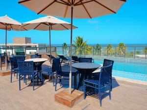 a patio with tables and chairs and a pool at Porto de Galinhas PORTO EXCLUSIVE BY AFT in Porto De Galinhas