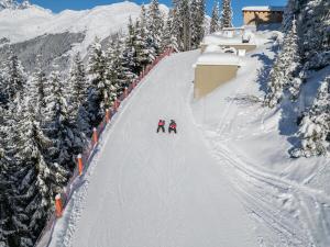 two people are skiing down a snow covered slope at Haus Dominik - Silvretta Card Premium Partner in See