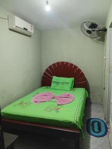 a small bedroom with a bed with a green blanket at Quarto de Pousada in Imperatriz