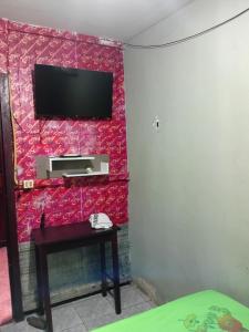 a room with a tv on a red wall at Quarto de Pousada in Imperatriz