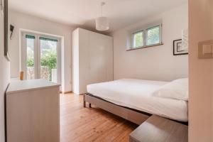 a white bedroom with a bed and a window at Villa Dream alla Beppa in Tenno