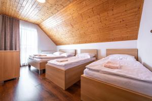 two beds in a room with a wooden ceiling at Chata Majocka Martin Strane, Ferrata in Martin