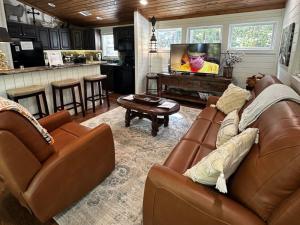 a living room with two brown leather couches and a tv at Hot Tub Firepit Dreams Streamside Hochatown in Broken Bow