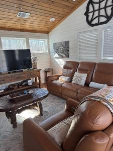 a living room with a couch and a flat screen tv at Hot Tub Firepit Dreams Streamside Hochatown in Broken Bow