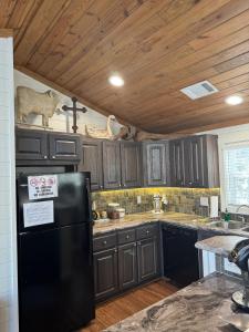a kitchen with a black refrigerator and wooden ceilings at Hot Tub Firepit Dreams Streamside Hochatown in Broken Bow +4 photos