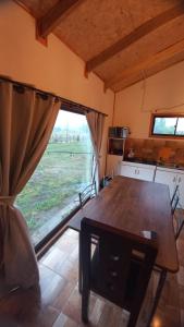 a kitchen with a wooden table and a large window at Cabañas 2 Aliwen Lonquimay in Lonquimay