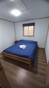 a large blue bed in a room with a window at Cabañas 2 Aliwen Lonquimay in Lonquimay