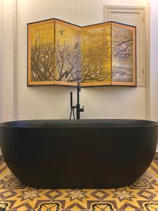 a black bath tub in a room with paintings at Casona de Santa Ana in Cuevas Bajas
