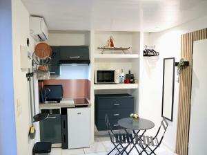 a small kitchen with a small table and a table and chairs at Domaine Maud-Jardin de Maud ! 100m plage in Saint-Pierre +6 photos