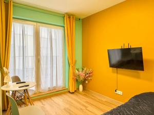 a bedroom with yellow walls and a tv on the wall at Rumia Apartment by JumpInHere in Rumia