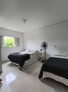 a white room with two beds and a fan at Casa Canto do Rio in Socorro