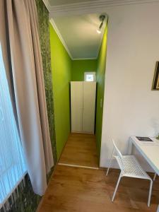 a room with a green wall and a desk and a chair at MaNo Apartman Siófok in Siófok
