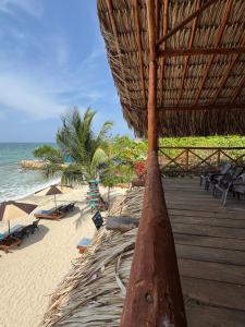a beach with a straw umbrella and chairs and the ocean at Merakai Hostel Rincon del Mar in Rincón