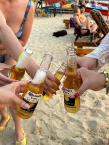 a group of people holding beer bottles on the beach at Merakai Hostel Rincon del Mar in Rincón