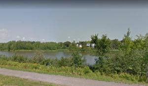 a body of water with trees and a road at Private Suite Jones Lake- West Moncton in Moncton +2 photos