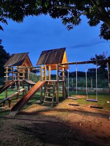 a group of wooden play structures with swings at Pousada Bom Jardim in Estivado