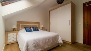 a bedroom with a white bed with blue pillows at Atico moderno en Langreo in Langreo