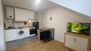 a kitchen with white cabinets and a tv in it at Atico moderno en Langreo in Langreo