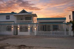 a white house with a sunset in the background at Carrasco Apartamentos in Nagua