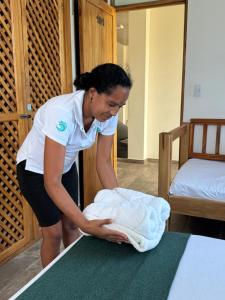 a woman is putting towels on a bed at Merakai Hostel Rincon del Mar in Rincón