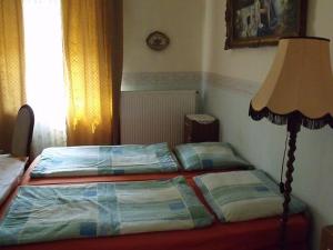 a bedroom with two twin beds and a lamp at Magdi Panzió in Hévíz