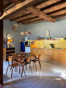 a large kitchen with a wooden table and chairs at Domaine Voilà in Génis