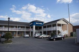 a hotel with cars parked in a parking lot at Valley Suites Extended Stay Hotel in Harrisonburg