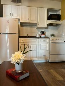 a kitchen with a refrigerator and a table with a vase of flowers at Valley Suites Extended Stay Hotel in Harrisonburg