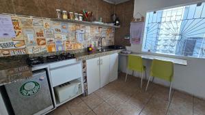 a kitchen with white cabinets and yellow chairs at Casa Aeroporto Pousada in Recife