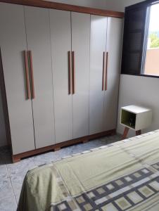 a bedroom with white cabinets and a bed at Casa de praia in Bertioga