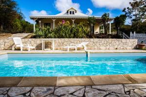 una piscina con dos sillas y una casa en Les Villas Créoles de Sainte-Anne, en Sainte-Anne