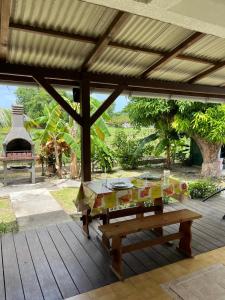 a wooden deck with a table and a bench at Les 2 Cocotiers - Studios in Sainte-Luce