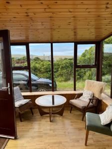 a living room with a table and chairs and windows at Leagarth House in Baltasound