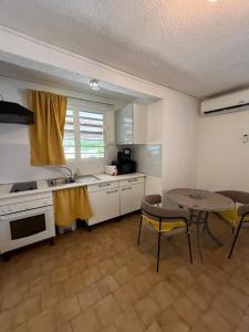 a kitchen with a table and a sink and a table and chairs at Les 2 Cocotiers - Studios in Sainte-Luce