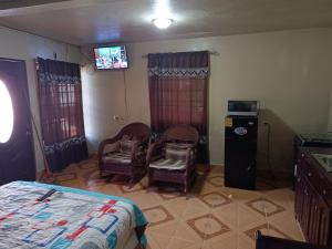 a bedroom with a bed and two chairs and a television at Sweet Dreams in Bluefields