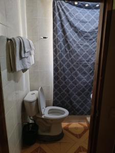 a bathroom with a toilet with a blue shower curtain at Sweet Dreams in Bluefields