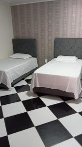 a bedroom with two beds and a checkered floor at Pousada da Isa in Quatro Barras +6 photos