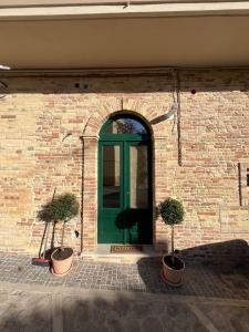a green door on a brick wall with two potted plants at A Casa di Costanza in Atri