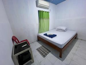 a small room with a small bed and a window at Ipoeng Rest Bed & Breakfast in Gorontalo +10 photos