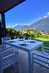 a white table with chairs and wine glasses at Bluelow Lakeview house in Dervio