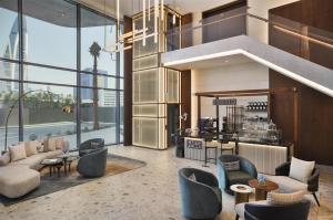 a living room with couches and chairs and a kitchen at Conrad Bahrain Financial Harbour in Manama