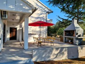 a patio with a table and a red umbrella at House Beachfront Delight in Neviđane