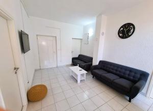 a living room with two black couches and a clock at House Beachfront Delight in Neviđane