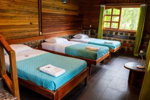 three beds in a room with wooden walls at Coati Lodge Misahualli in Tena
