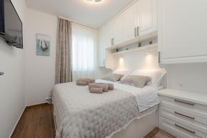 a white bedroom with a bed with two brown towels on it at Villa Ursula in Pakoštane +43 photos