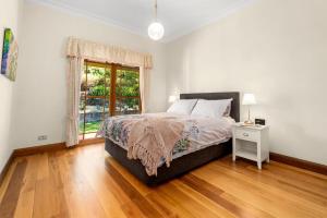 a white bedroom with a bed and a window at Tiverton in Kurrajong