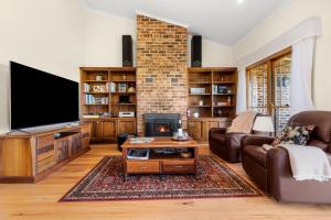 a living room with a fireplace and a flat screen tv at Tiverton in Kurrajong