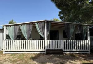 a white house with a white fence and curtains at Dalmacia Idyll mobilházak Privlaka in Privlaka
