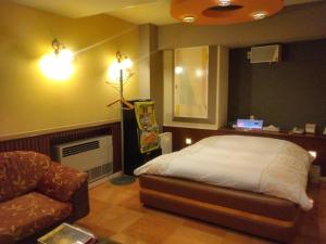 a bedroom with a bed and a couch and a chair at ホテルスター in Iwaki
