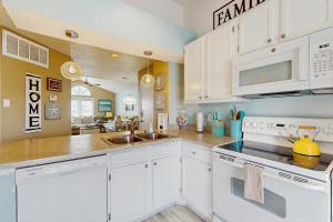 a kitchen with white cabinets and a sink at Beach Club: The Lighthouse in Padre Island